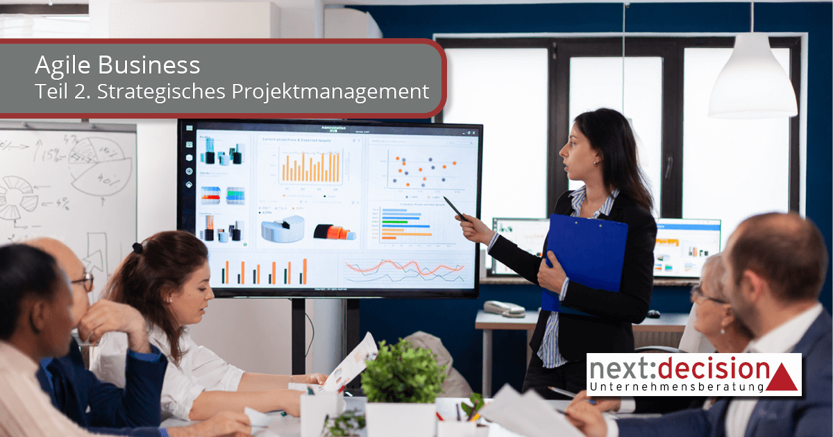 Bild eines Geschäftsmeetings. Eine junge Frau steht vor einer digitalen Tafel und zeigt auf die unterschiedlichen Diagramme. Das Bild vermittelt konzentriertes Arbeiten.